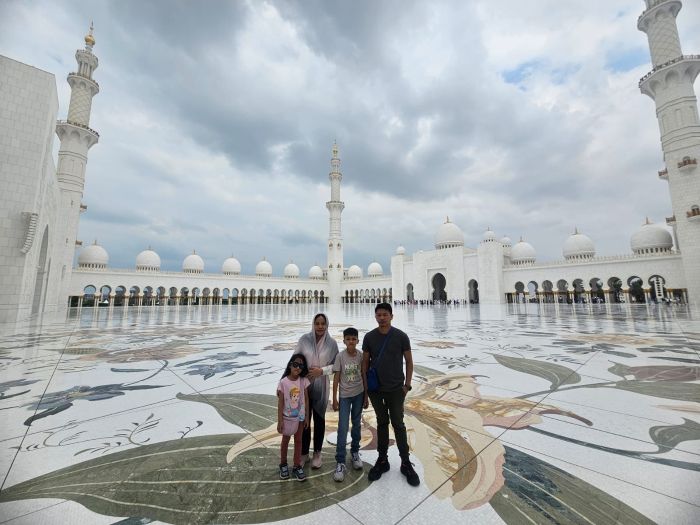 Sheikh Zayed Grand Mosque Courtyard, Grand Mosque Exterior at Sunset, Chandelier in the Main Prayer Hall, World's Largest Hand-Knotted Carpet, Intricate Column Design, Reflective Pools at Night, Visitors in the Mosque's Courtyard, Guided Tour in Progress, Aerial View of the Mosque, Women in Traditional Abayas