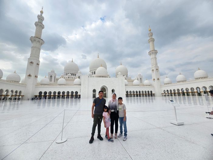 Sheikh Zayed Grand Mosque Courtyard, Grand Mosque Exterior at Sunset, Chandelier in the Main Prayer Hall, World's Largest Hand-Knotted Carpet, Intricate Column Design, Reflective Pools at Night, Visitors in the Mosque's Courtyard, Guided Tour in Progress, Aerial View of the Mosque, Women in Traditional Abayas